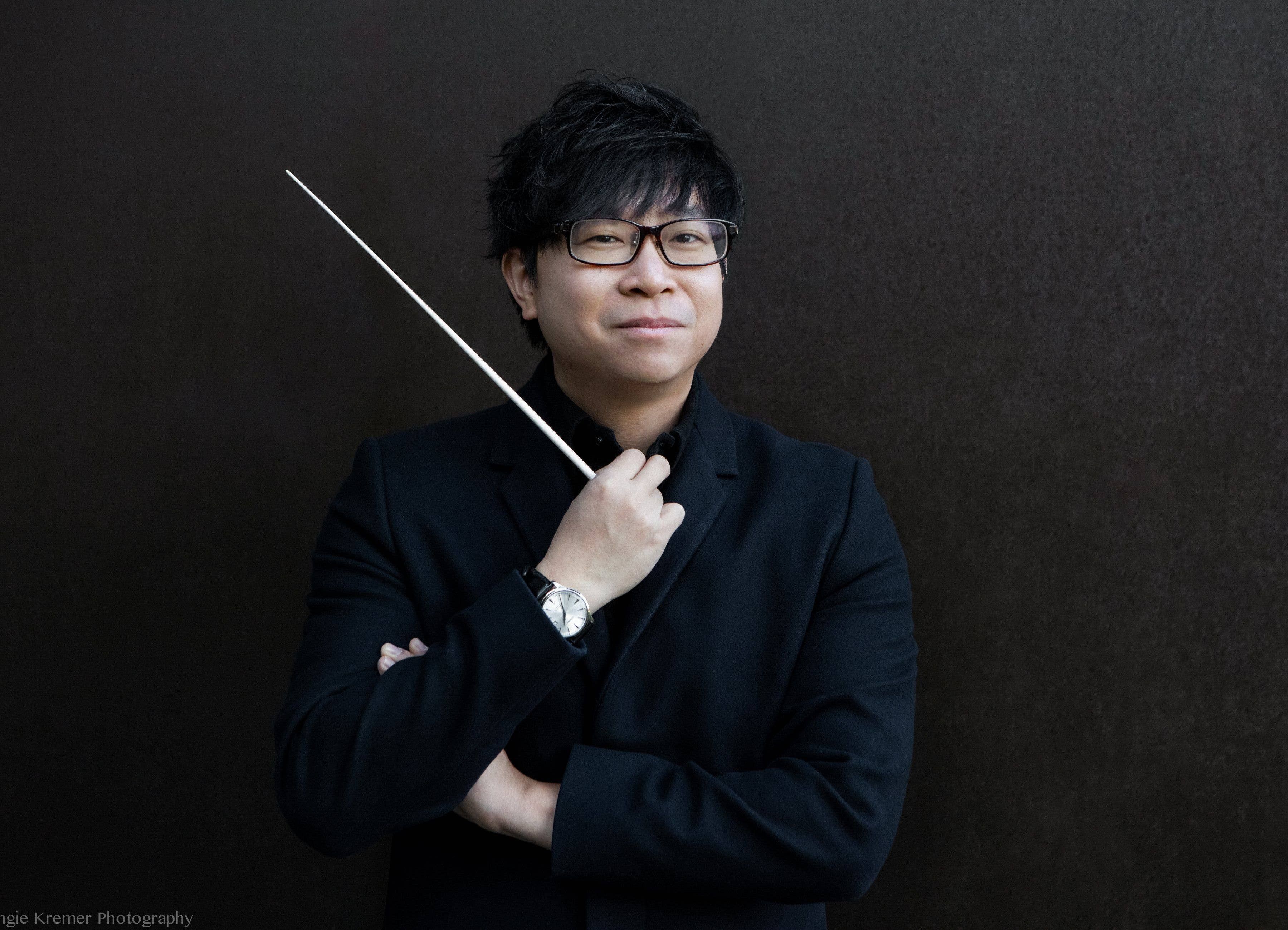Kahchun Wong holding a conductor’s baton in a confident pose